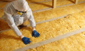 Man installing thermal roof insulation layer using mineral wool.