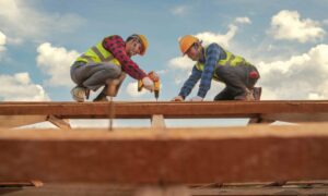 Construction expertise male roofer carpenter wear safety uniform working on roofs structure on construction site
